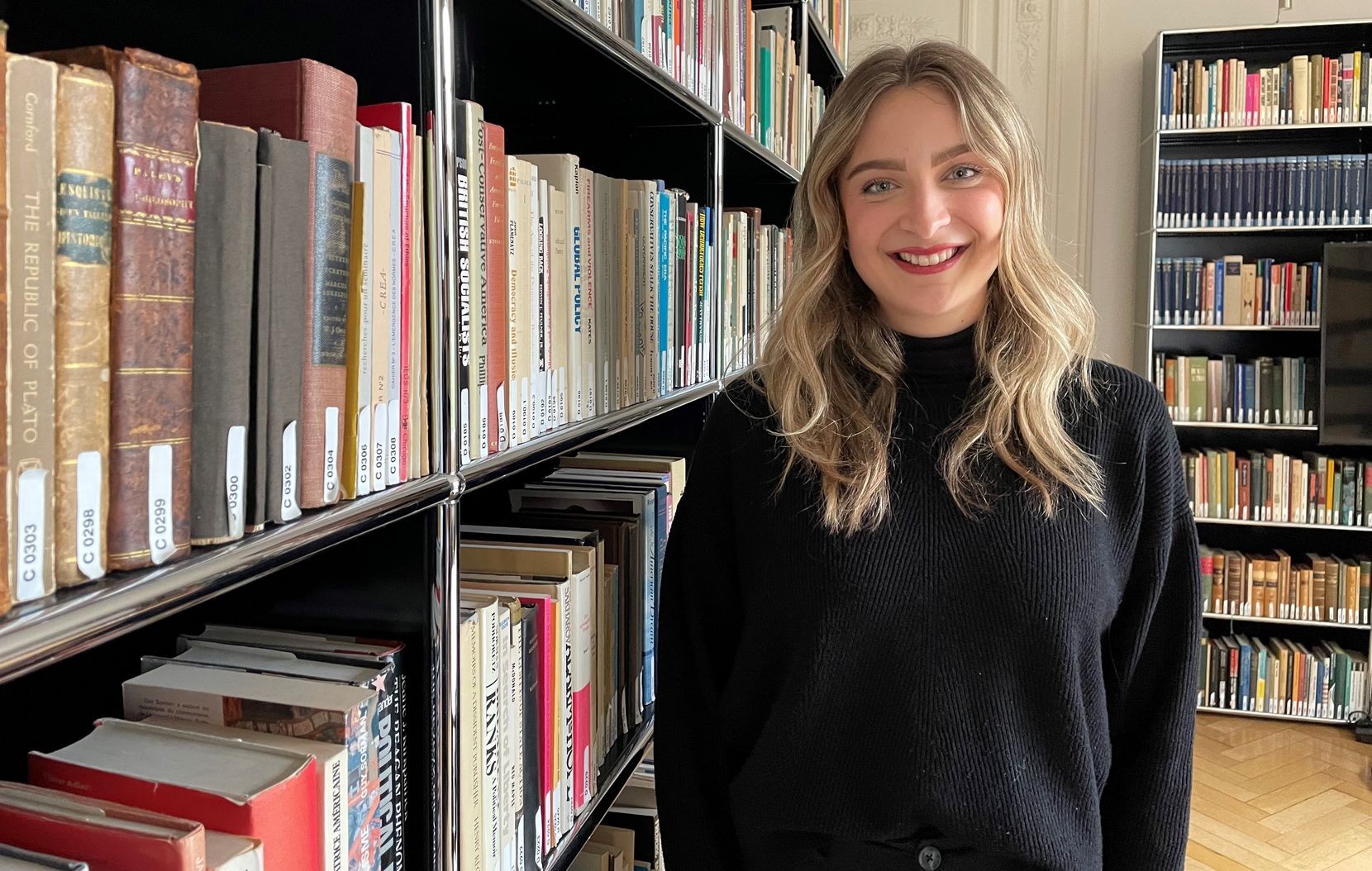 Eine junge Frau aus dem Zürcher Oberland steht vor einem Bücherregal.