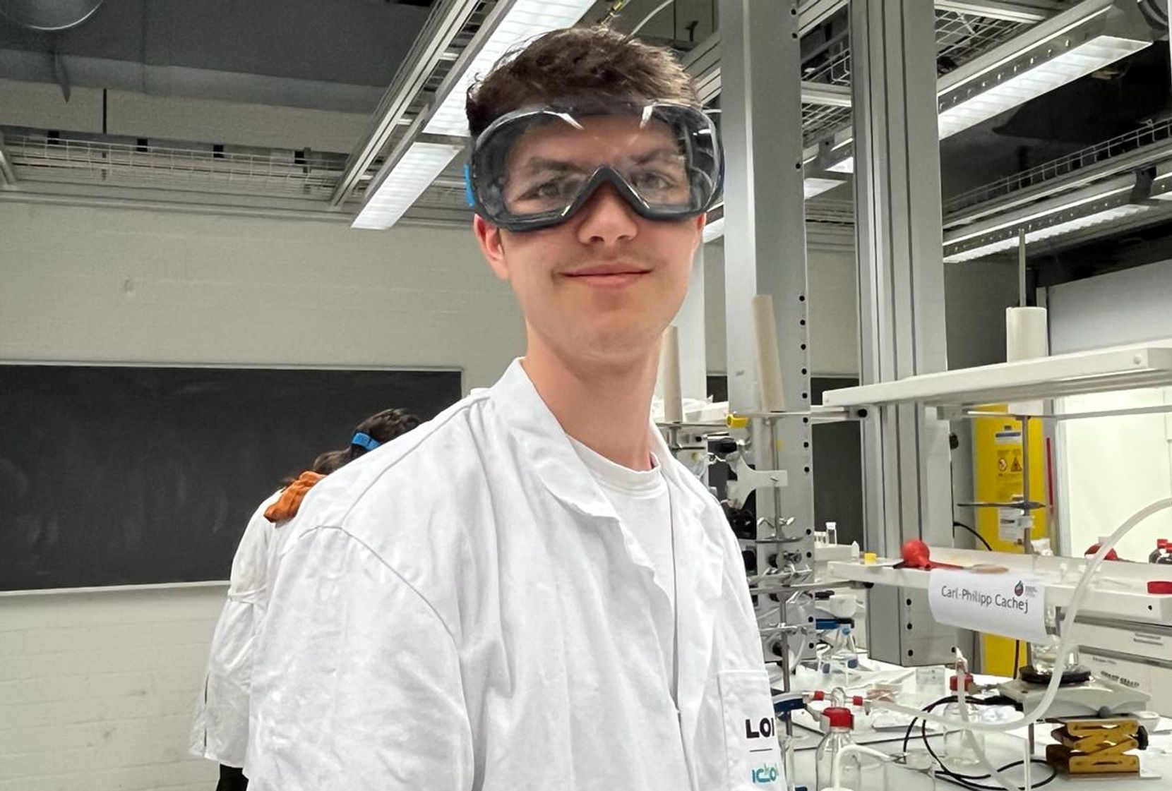 Man sieht Andrin Hauenstein im Chemielabor mit einer Schutzbrille.