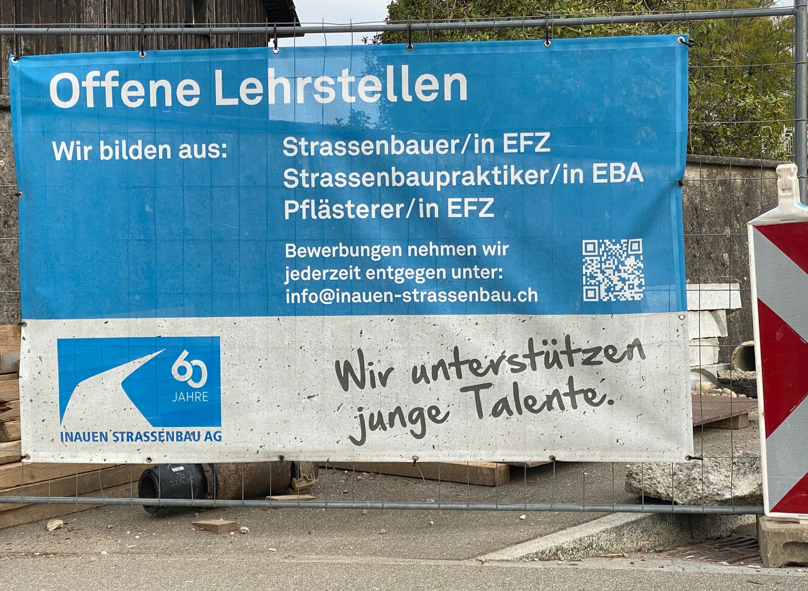 An einer Baustelle hängt ein Plakat der Inauen Strassenbau AG, auf dem Lernende gesucht werden.
