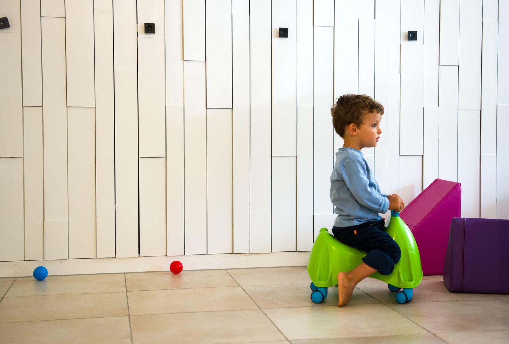 Ein Kind fährt auf einem Spielzeug mit Rädern vorbei. 