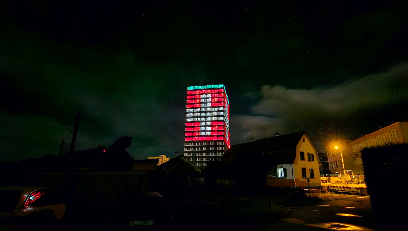 Ein Hochhaus ist in den Schweizer Landesfarben von innen beleuchtet.