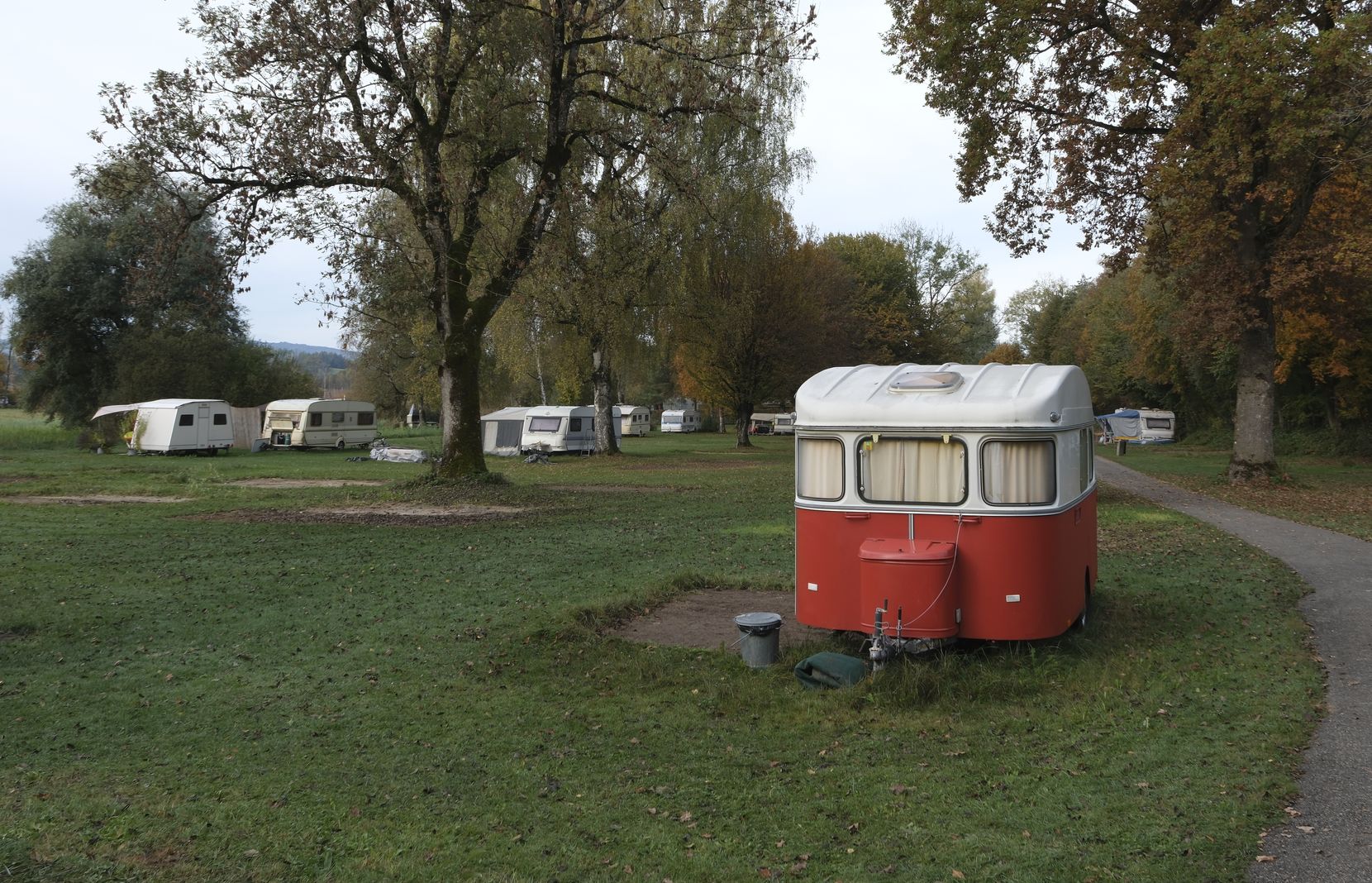 Auf dem Bild ist ein roter Wohnwagen auf dem Areal des Campingplatzes Auslikon zu sehen.
