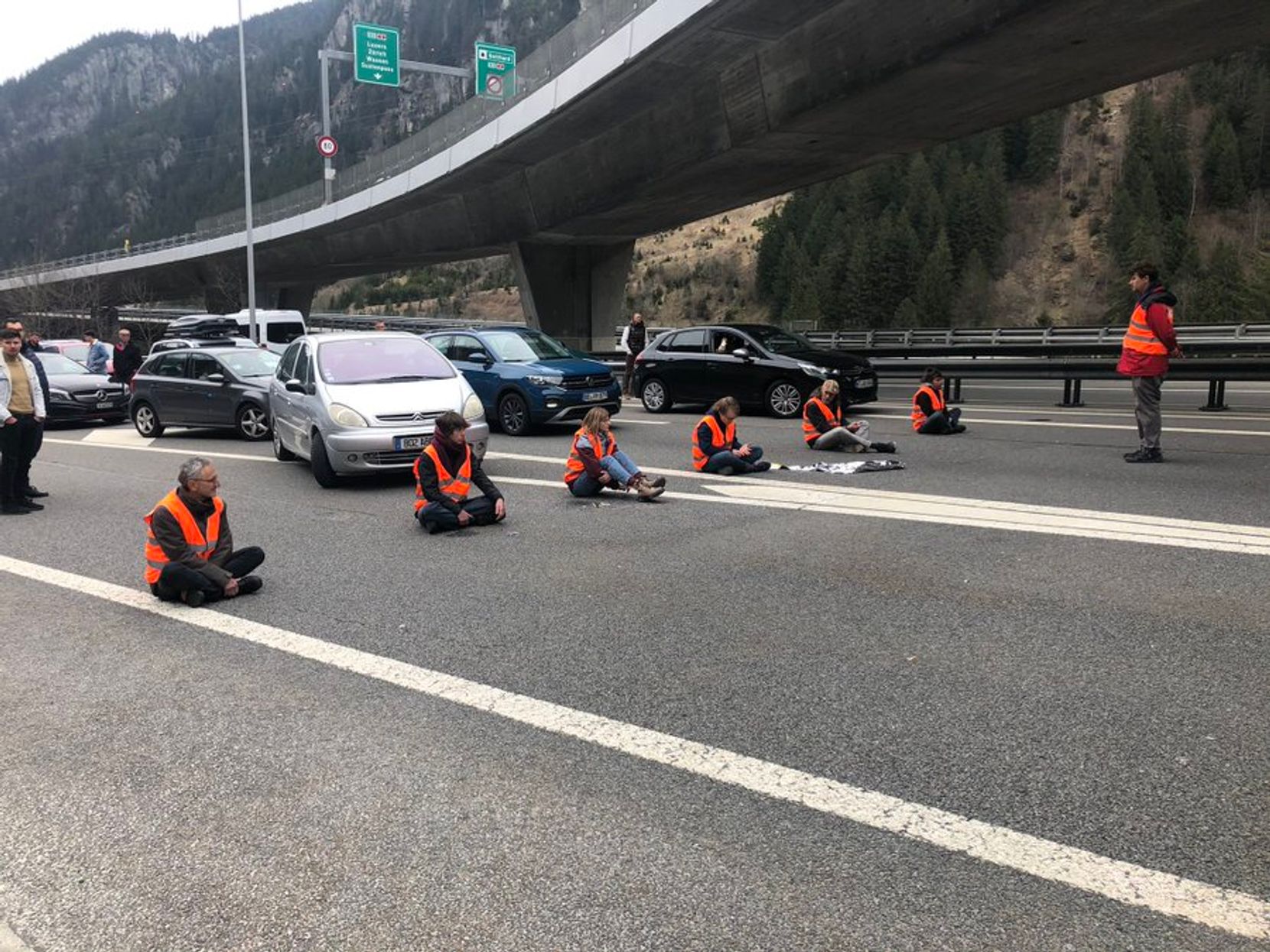 Menschen sitzen auf der Autobahn und blockieren den Weg zum Gotthardtunnel