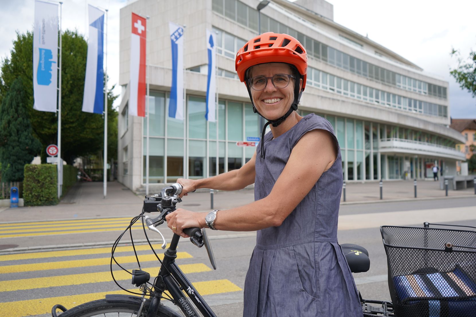 Eine Frau steht neben dem Fahrrad vor dem Stadthaus.