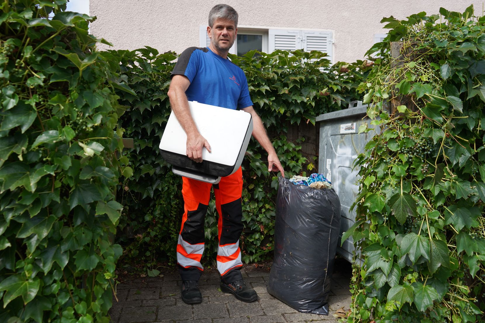 Ein Mann zeigt auf einen Abfallsack.