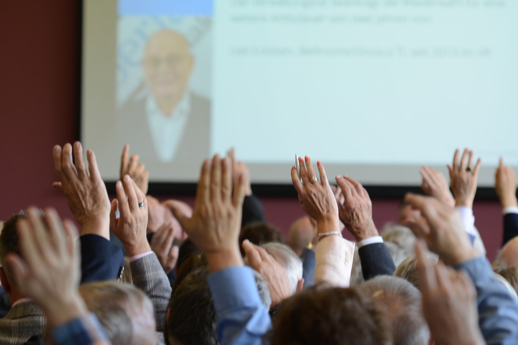 Menschen halten für eine Abstimmung ihre Hände hoch
