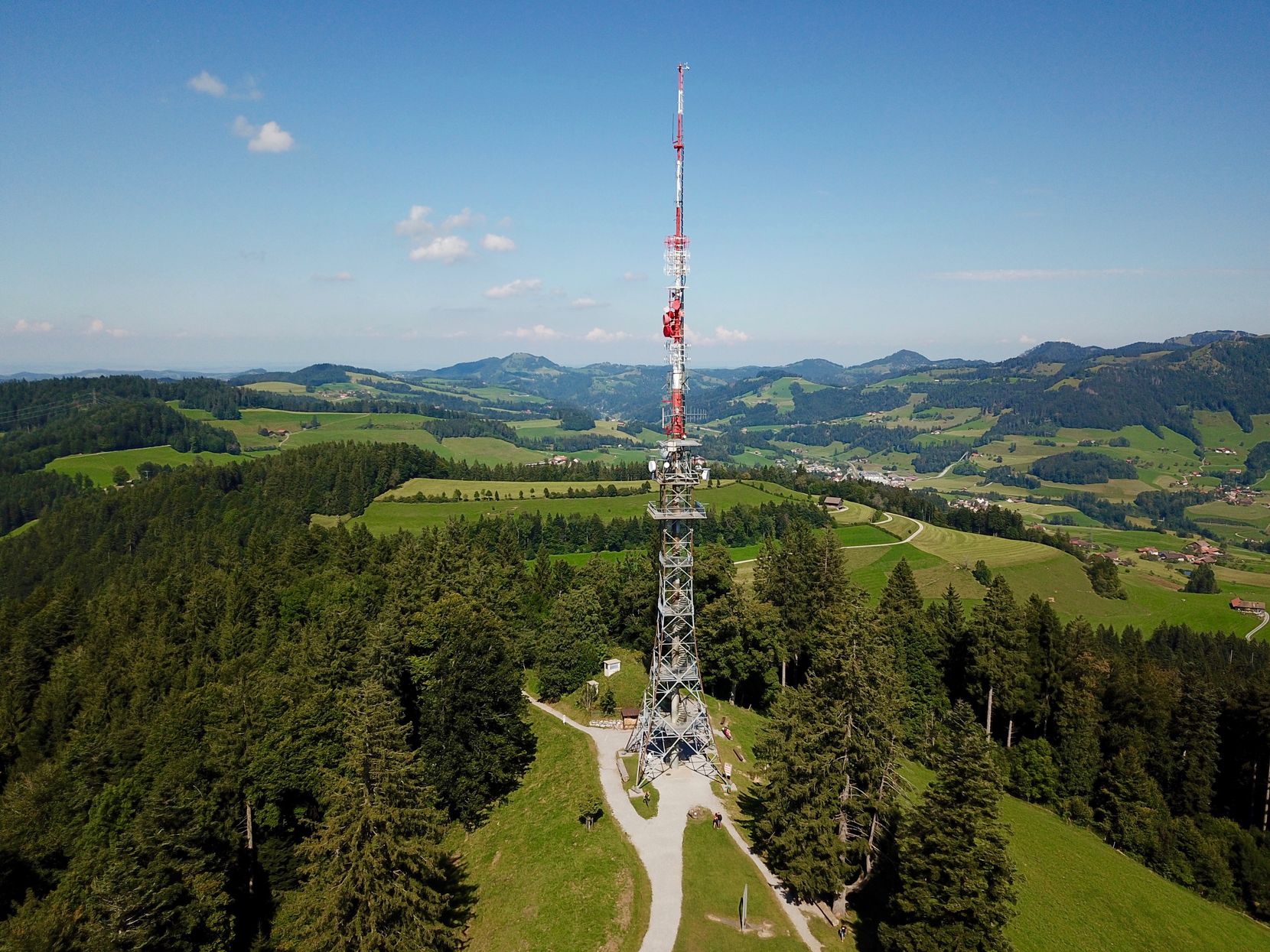 Ein Turm auf einem Hügel, der von Waldgebieten umgeben ist. 