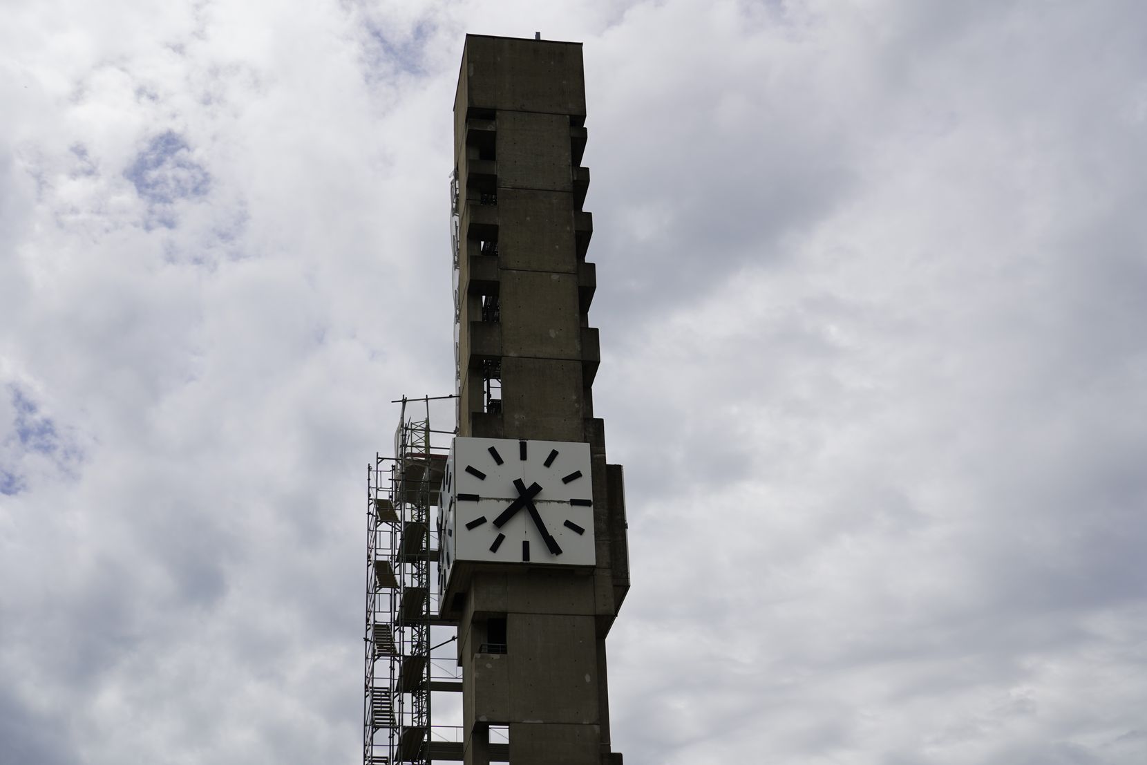 Ein Glockenturm mit Gerüsten unter wolkigem Himmel.