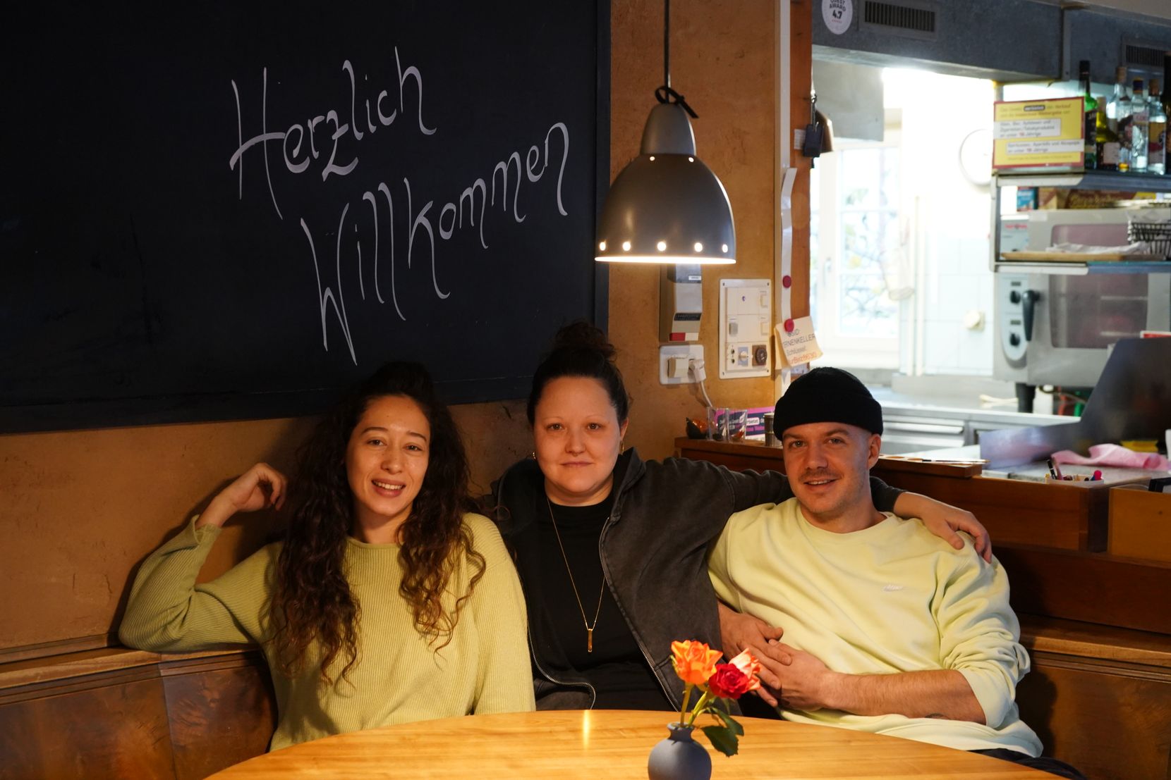 Drei junge Leute sitzen an einem Stammtisch in einem Restaurant.