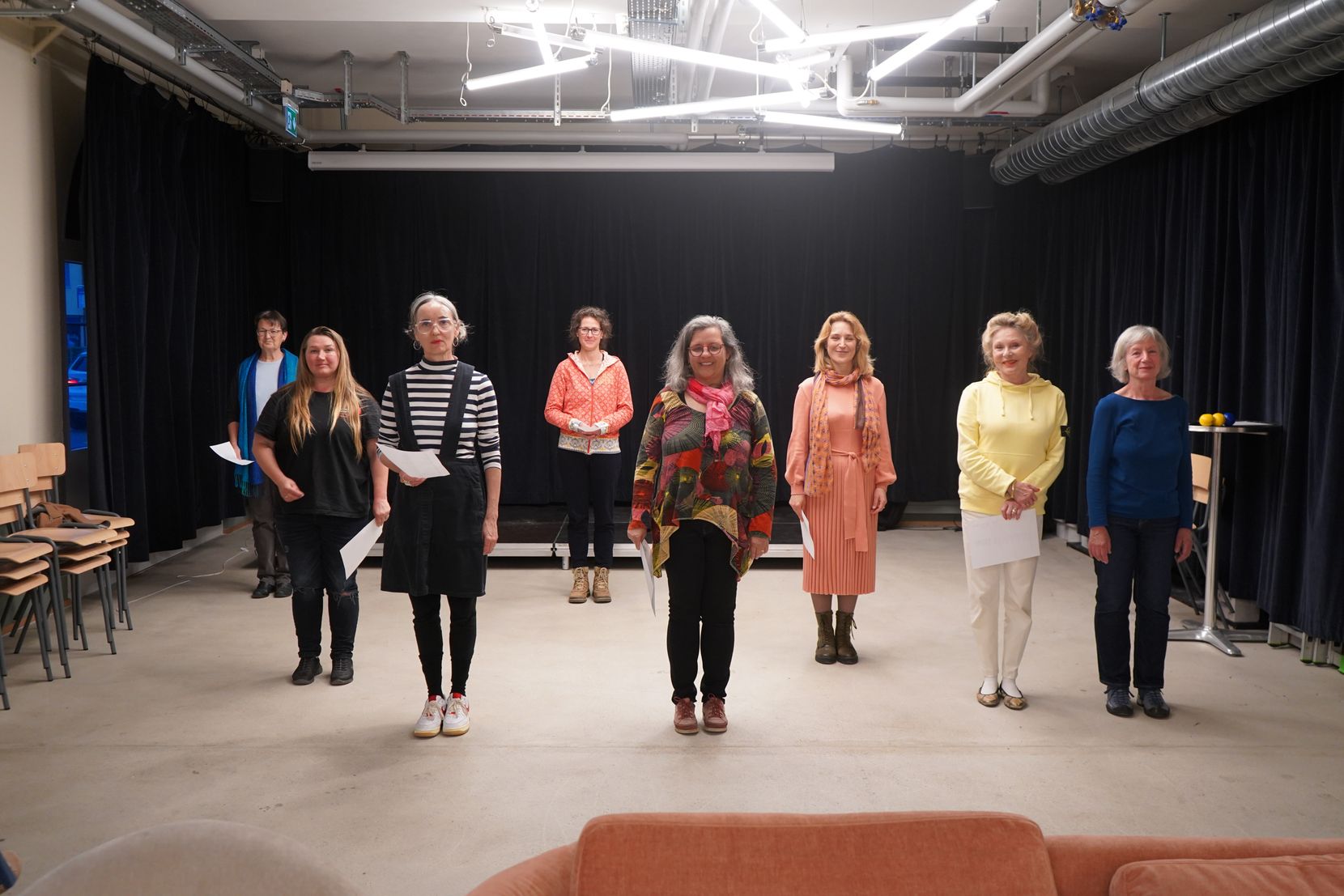 Theaterproben in einem Wetziker Lokal mit Bühne. Acht Frauen stehen nebeneinander, sie tragen bunte Kleidung.