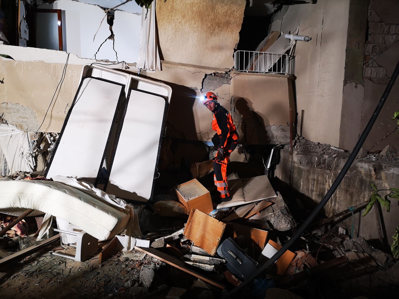 Ein Rettungshelfer steht auf Trümmern eines von einem Erdbeben zerstörten Hochhauses.