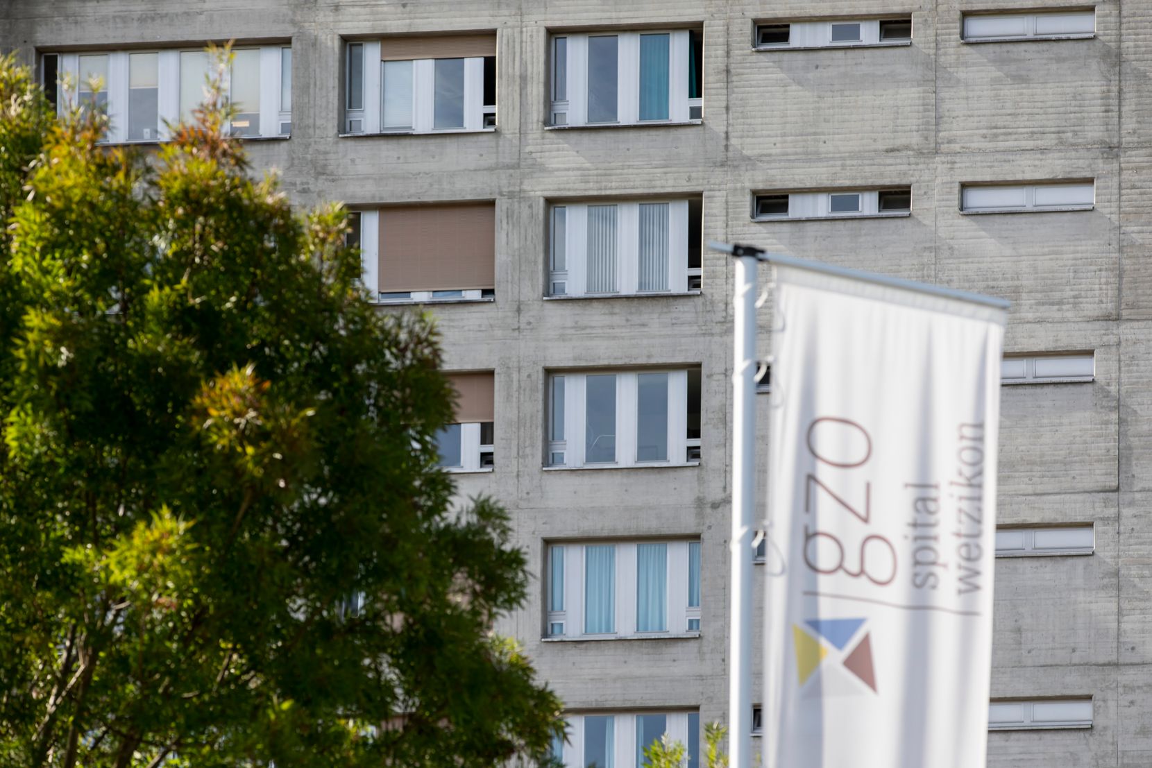 Eine unscharfe Fahne des GZO-Spitals Wetzikon im Vordergrund, im Hintergrund das Krankenhaus.