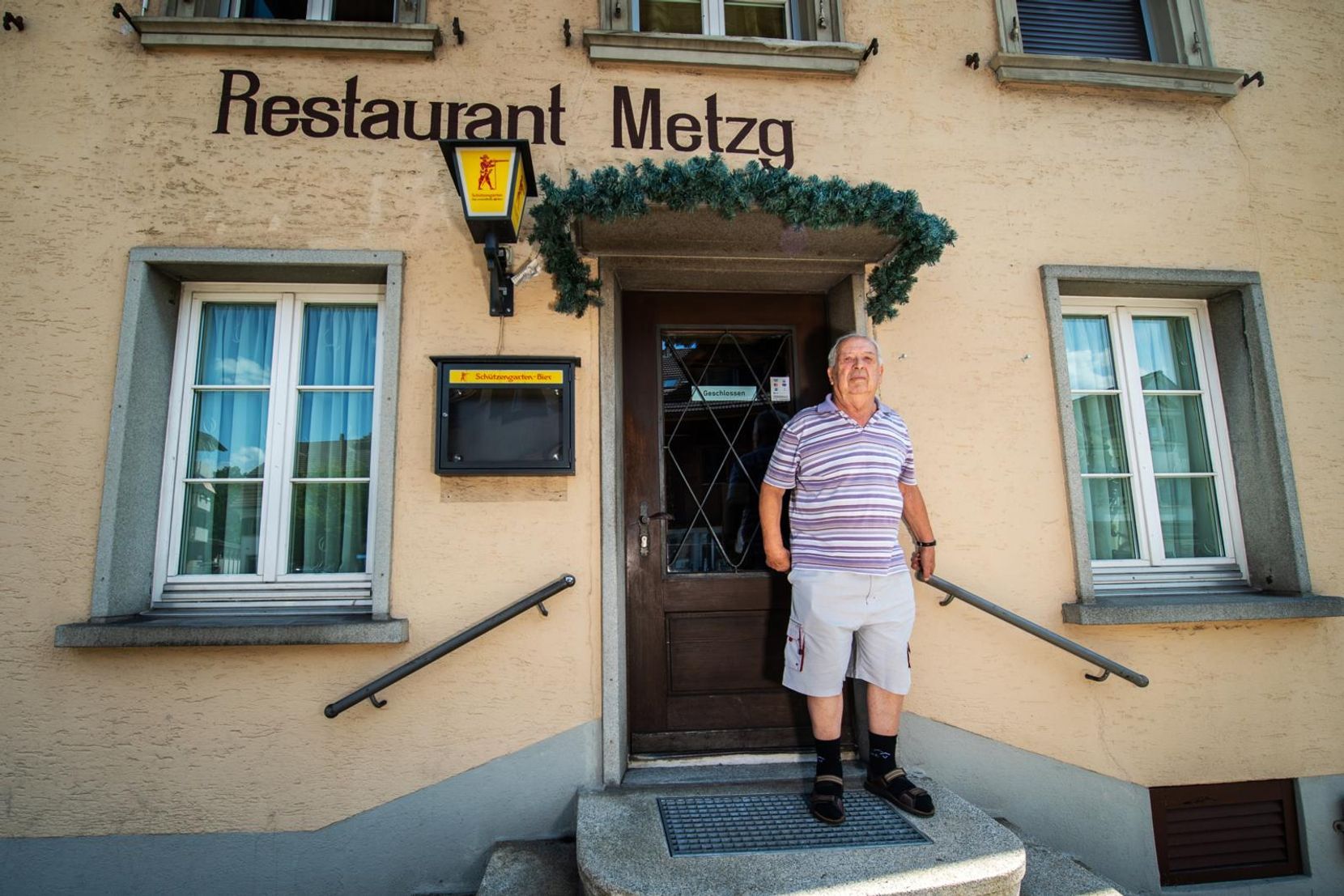 Man sieht einen Mann, der auf einer Treppe vor einem Restaurant steht.