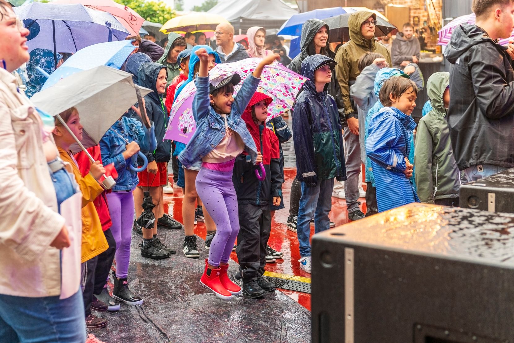Kinder tanzen im Regen bei der Bühne.