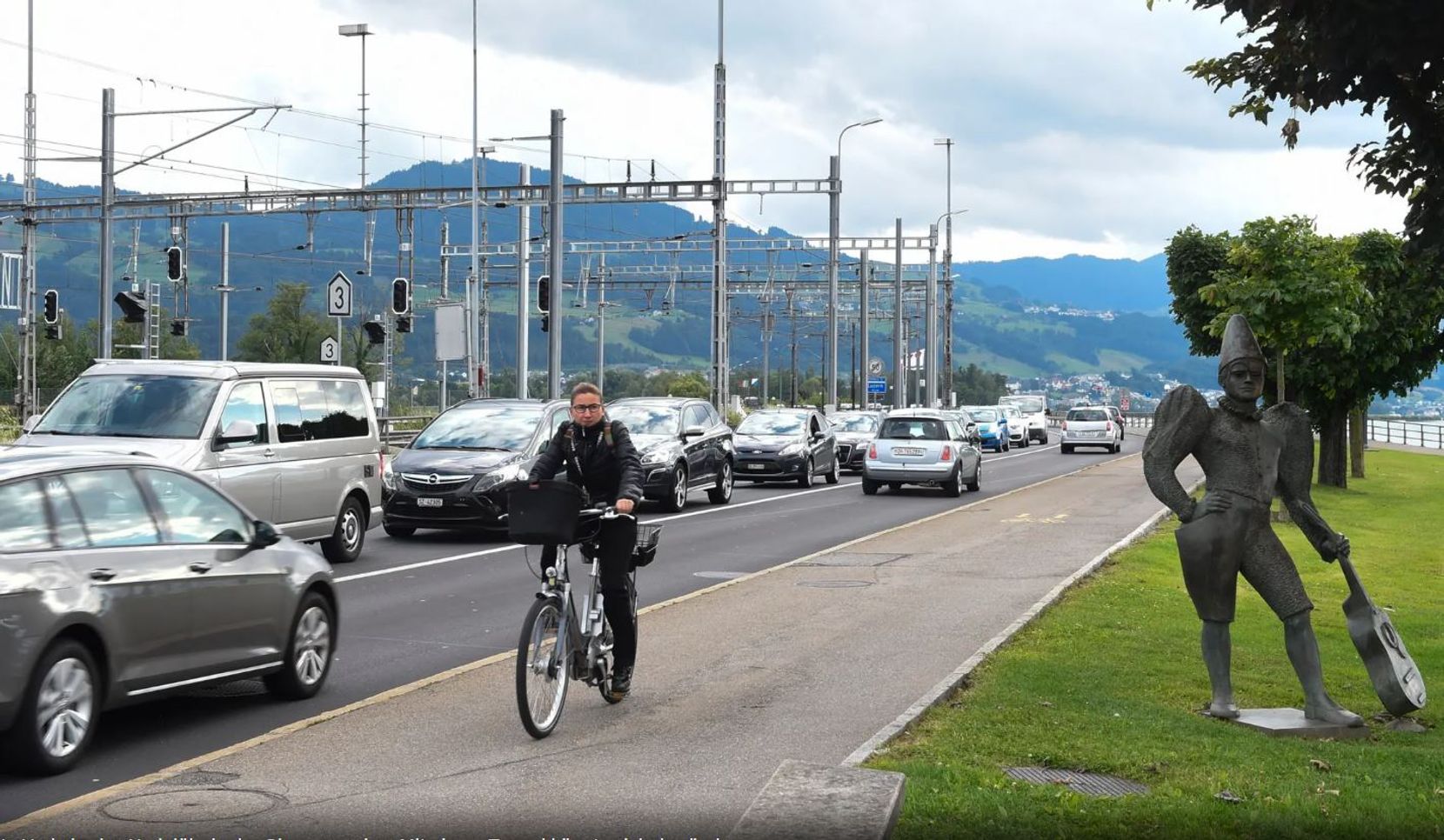 Autos stauen sich, eine Velofahrerin fährt vorbei. 