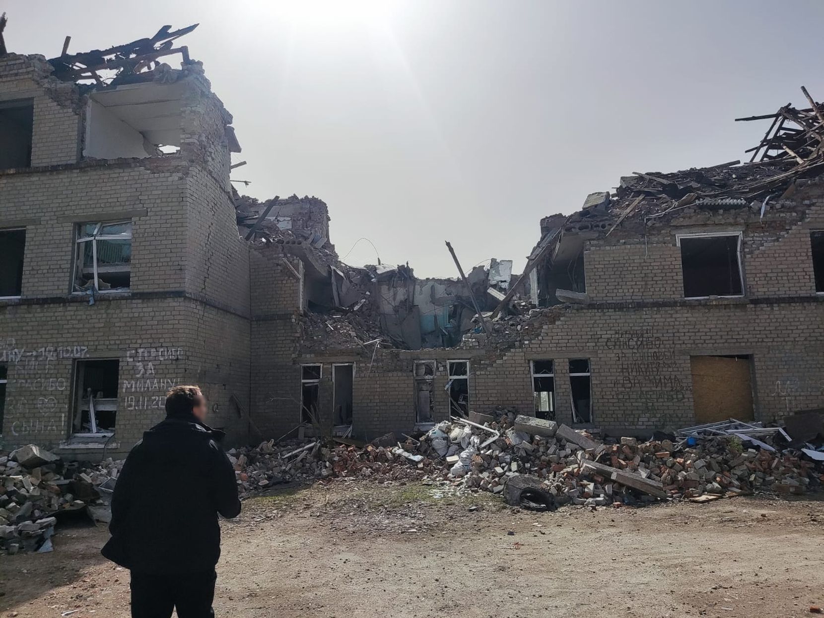 Ein Mann steht vor einem zerbombten Gebäude.