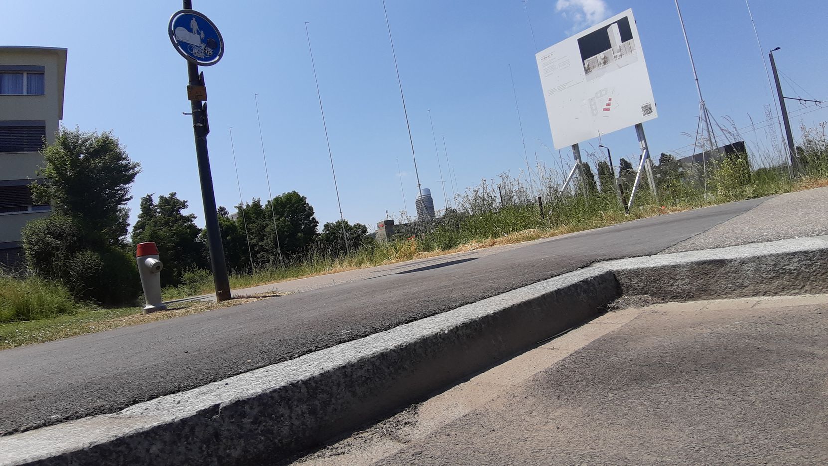 Randstein an einer Strasse, dahinter ein Baugespann. 