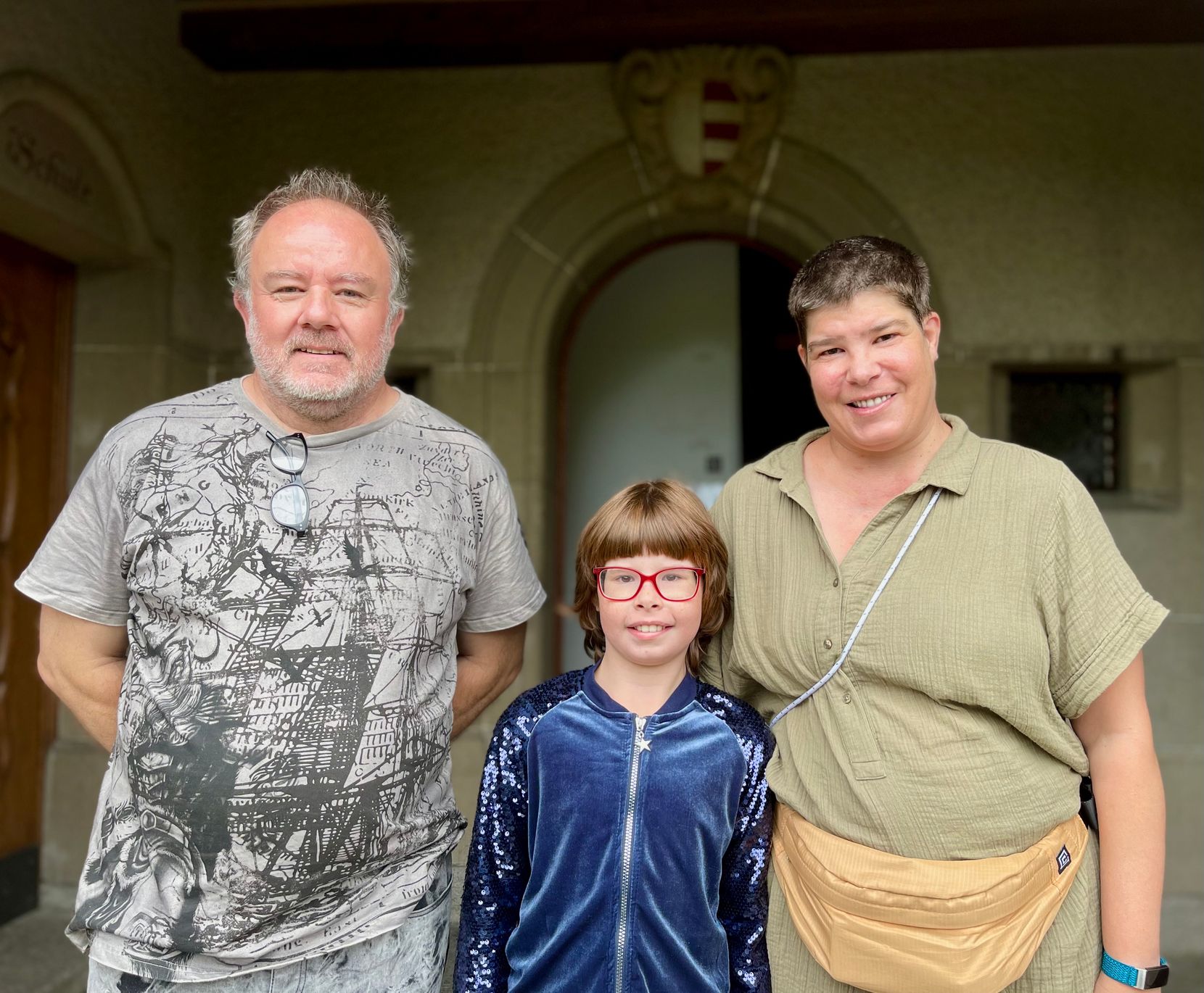 Man sieht ein Mädchen zusammen mit einer Frau und einem Mann.