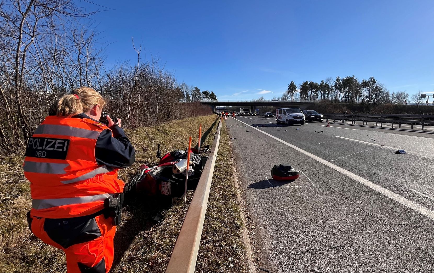 Eine Polizistin fotografiert die Unfallstelle eines Motorradunfalls beim Brüttiseller Kreuz. Ein Motorrad liegt neben der Leitplanke.
