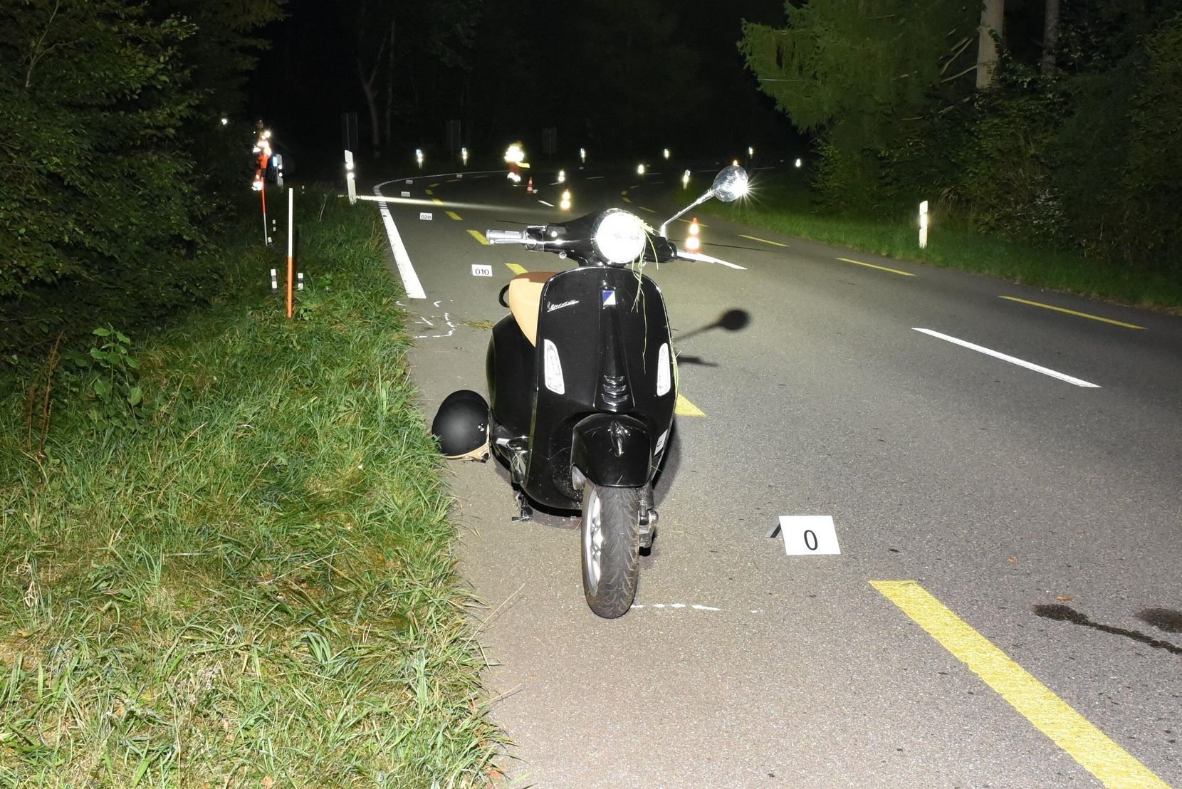Ein defekter Roller steht nachts auf einer abgesperrter Strasse. 