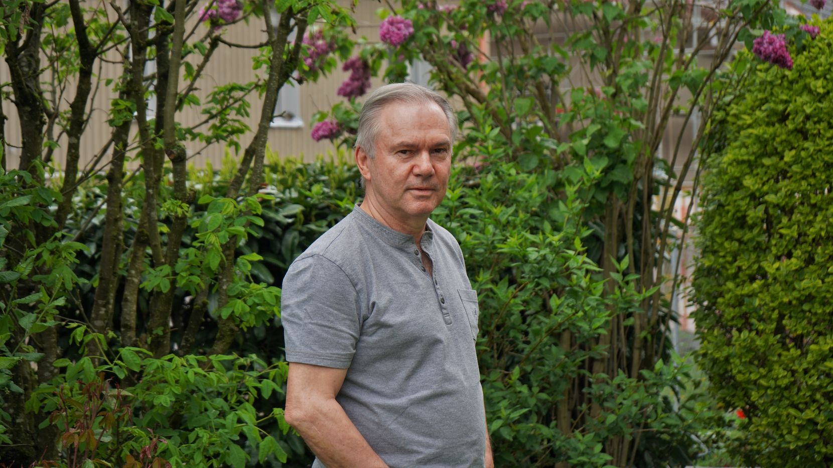Mann steht vor Pflanzen im Garten.