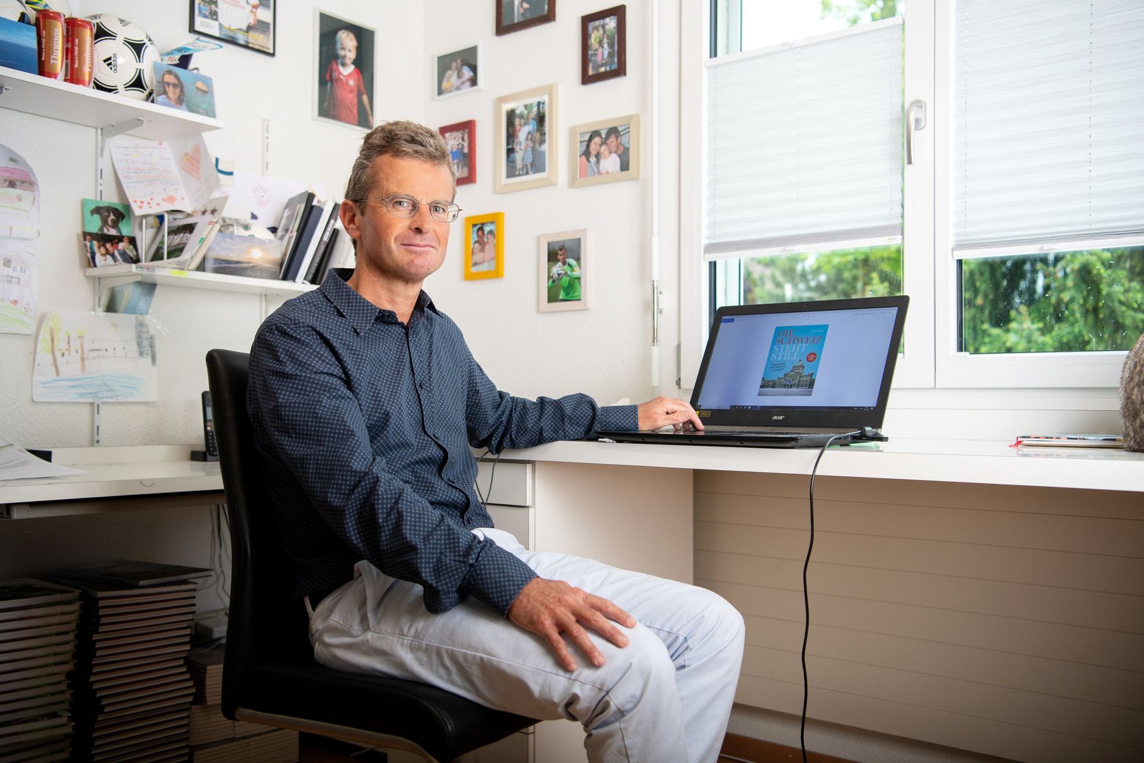 Der Autor Thomas Renggli sitzt in seinem Büro vor einem Notebook. 
