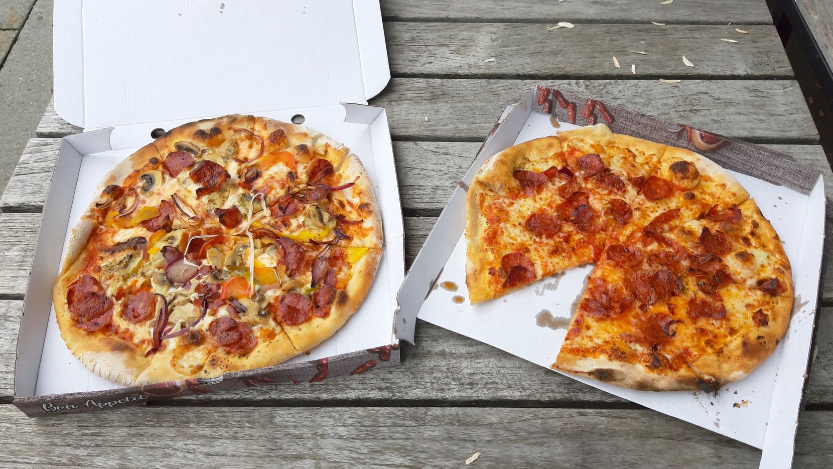 Zwei Pizzas in je einer Pizzaschachtel.