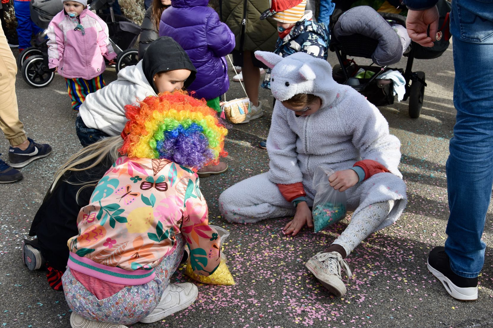 Kinder mit farbigen Konfettis sitzen am Boden.