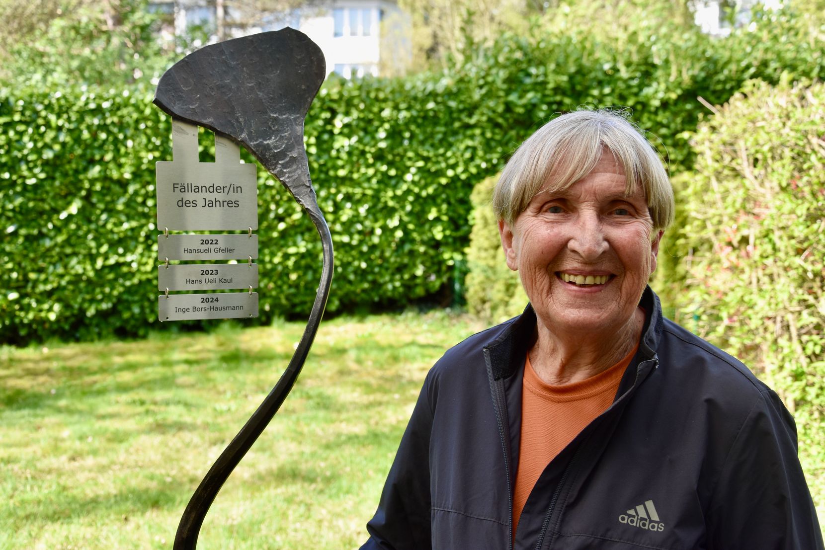 Eine Frau steht lächelnd neben einer Eisenplastik mit der Aufschrift «Fällander/in des Jahres».