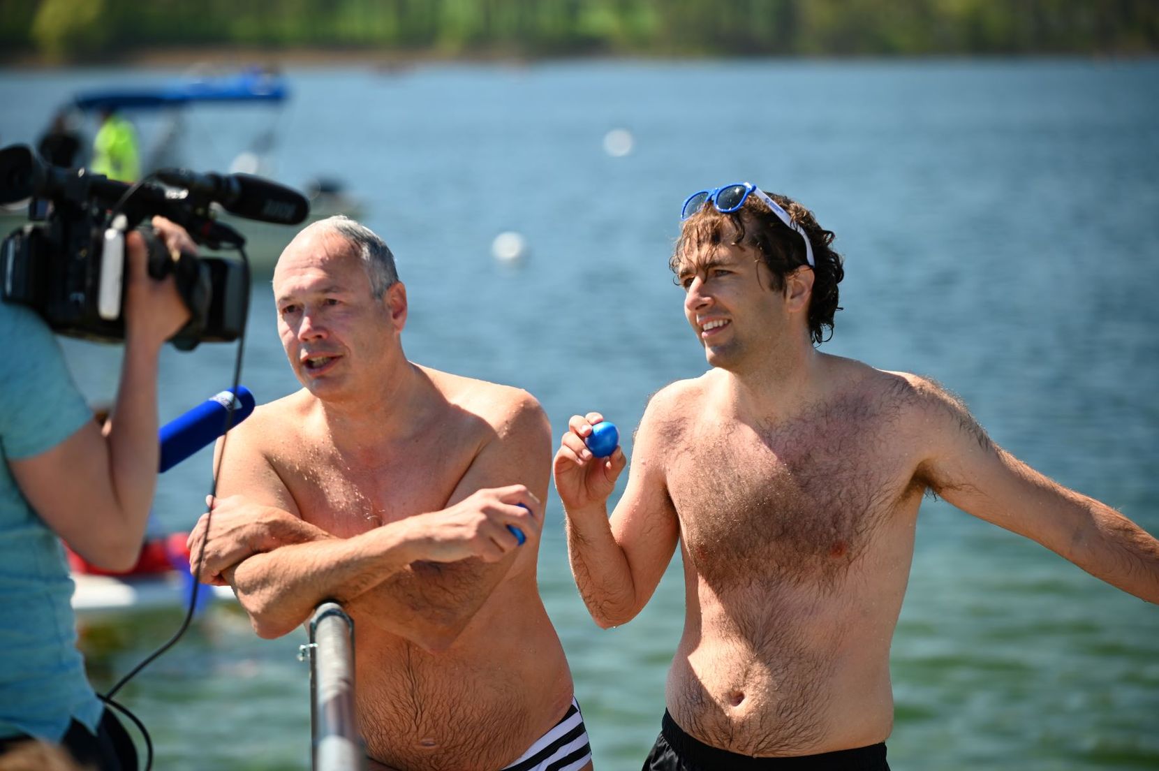 Harald Müller (links) und Simon Michel (rechts) stehen beim Blaueierschwimmen am Greifensee mit einem blauen Ei in der Hand.