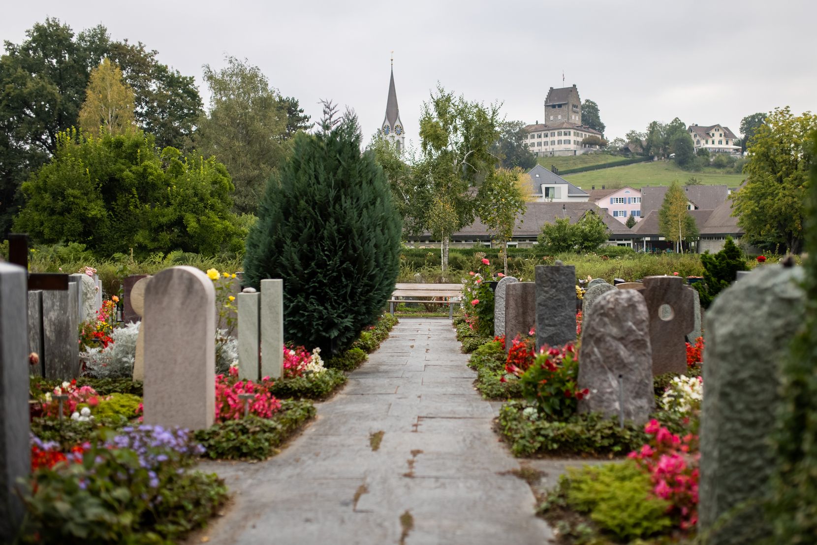 Grabsteine auf dem Ustermer Friedhof, im Hintergrund sind die Dienstgebäude zu sehen. 