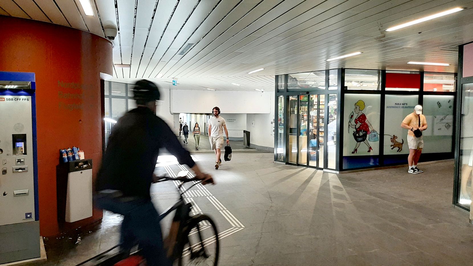 Beschilderung und Velofahrer im Bereich der Bahnhofsunterführung in Dübendorf.
