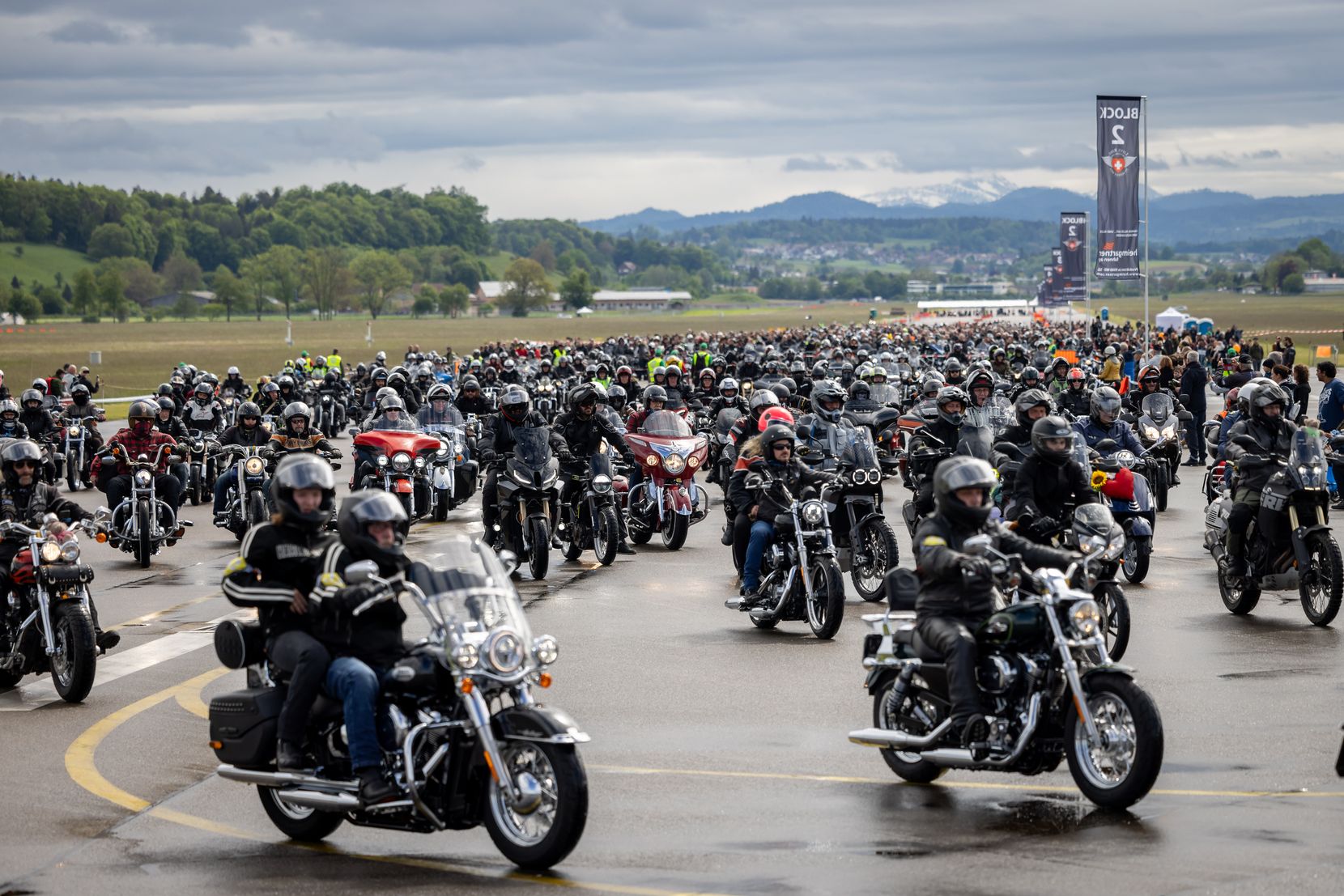 Hunderte Motorräder setzen sich auf einem  Rollfeld eines Flugplatzes in Bewegung. 