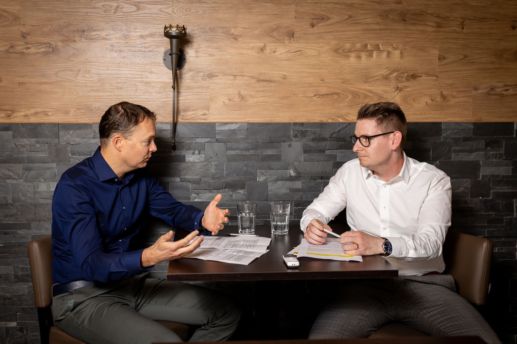 Zwei Männer sitzen an einem Tisch und diskutieren.