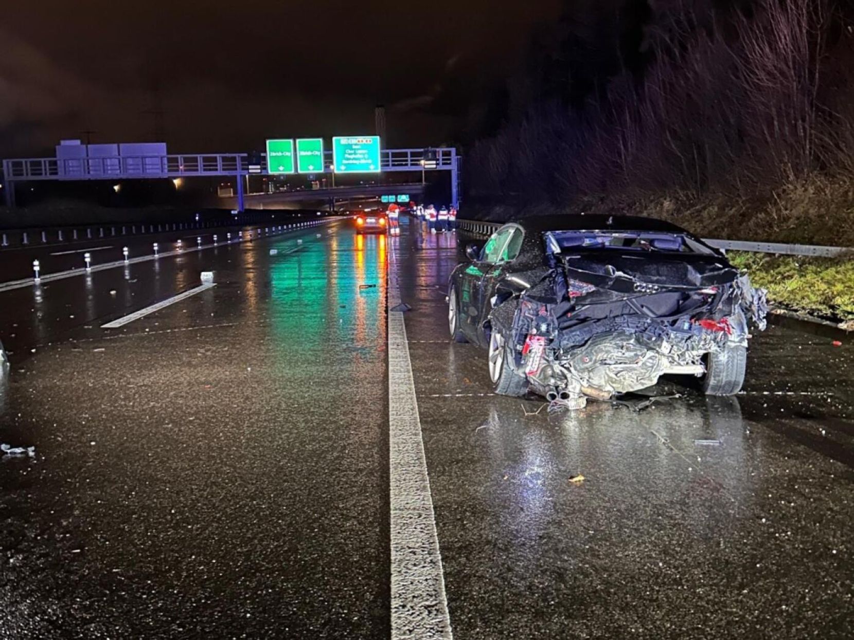 Man sieht eine Autobahn bei Nacht. Auf dem Pannenstreifen steht ein Unfallauto.