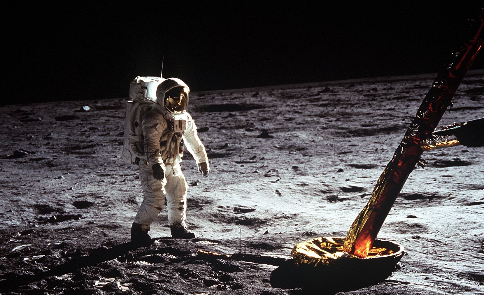 Ein Astronaut auf dem Mond, neben ihm ein Bein der Mondfähre.