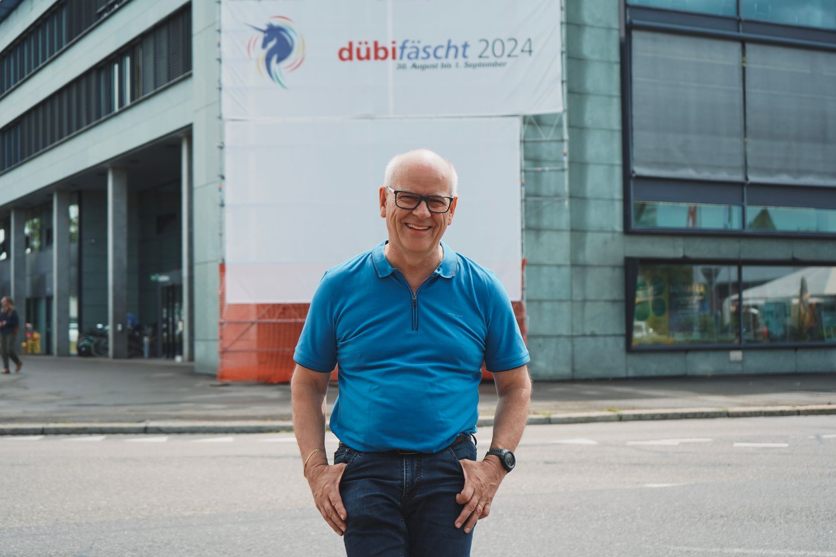 Im Fokus des Fotos steht ein Mann in einem blauen Shirt. Hinter ihm ist das Stadthaus von Dübendorf zu sehen. 