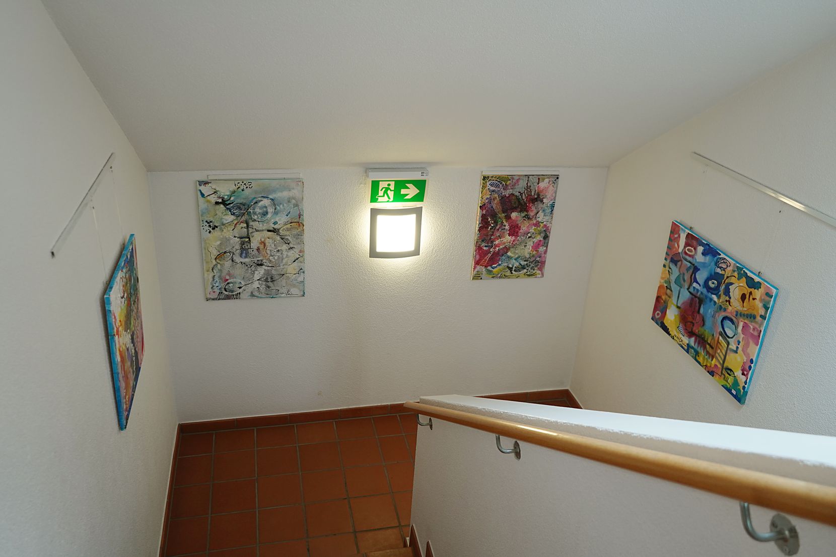 Vier gemalte Bilder in einem Treppenhaus.