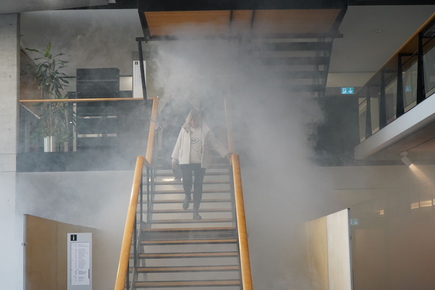 Mehrere Mitarbeiterinnen des Stadthauses laufen durch den Rauch die Treppe herunter.