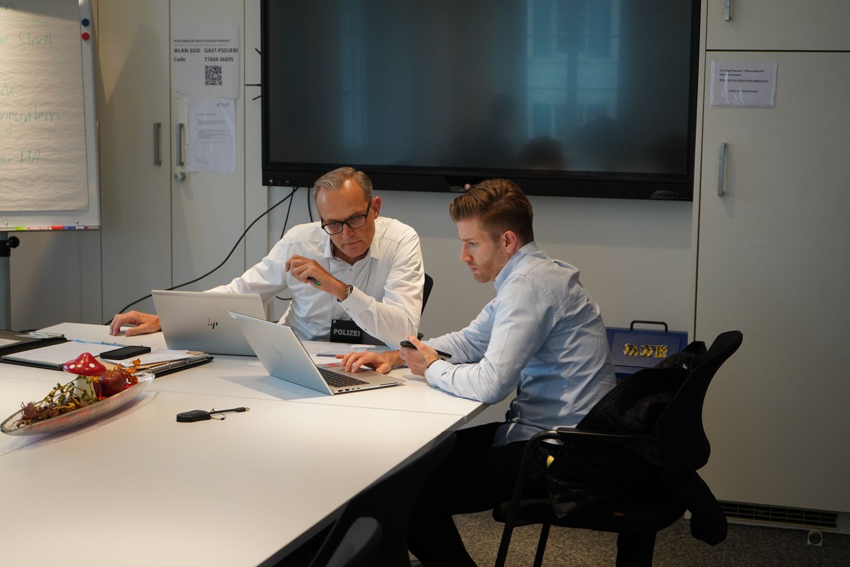 Patrick Céréda, Chef Medienabteilung der Kapo, und Rico Roffler, stellvertretender Stadtschreiber, sitzen in einem Sitzungszimmer.