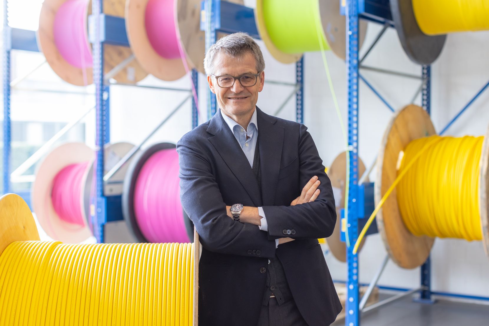 Michel Riva, CEO der Wetziker R&M-Gruppe, mit verschränkten Armen, an eine gelbe Kabelrolle gelehnt.