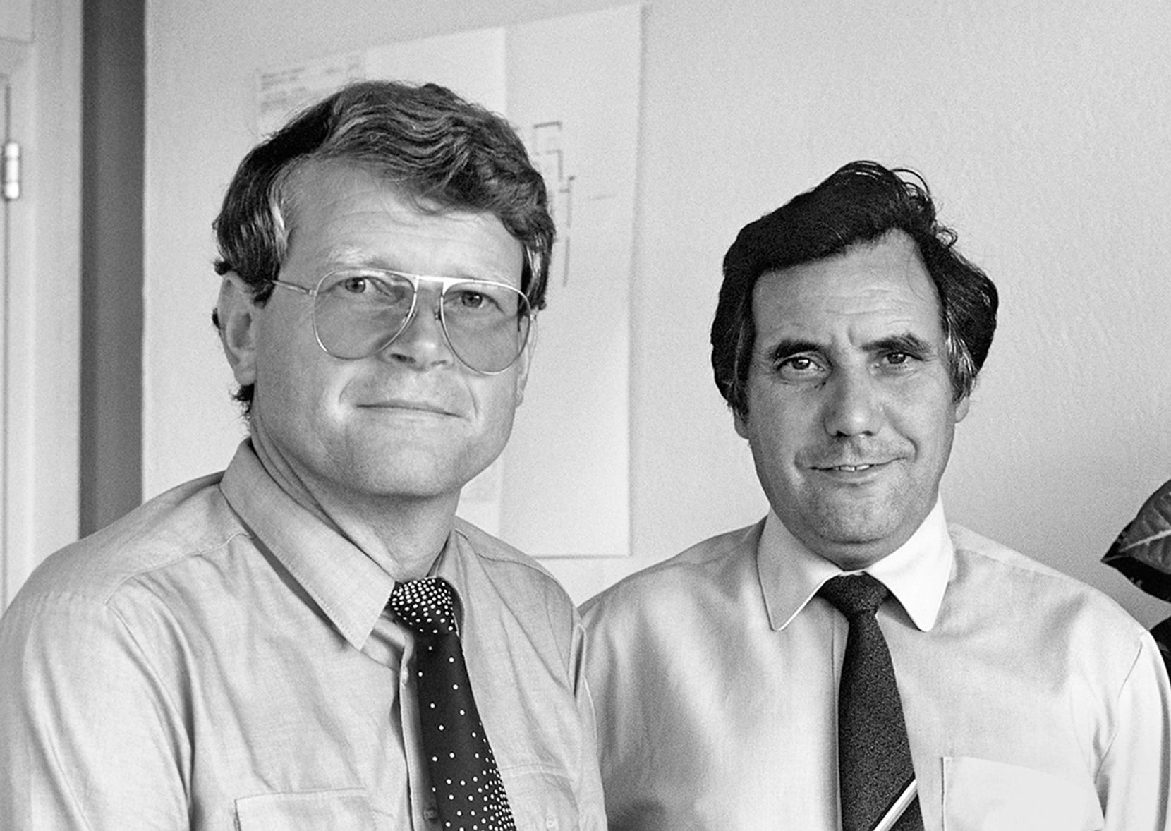 Schwarz-Weiss-Bild zweier Männer mit Hemd und Krawatte.