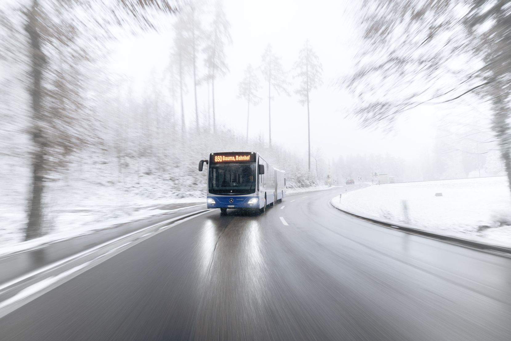 Ein Bus fährt durch eine verschneite Landschaft.
