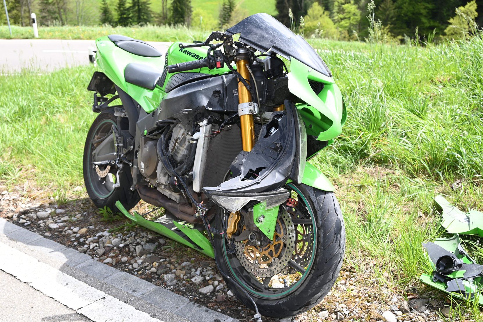 Man sieht ein grünes Motorrad, das nach einem Sturz beschädigt ist.