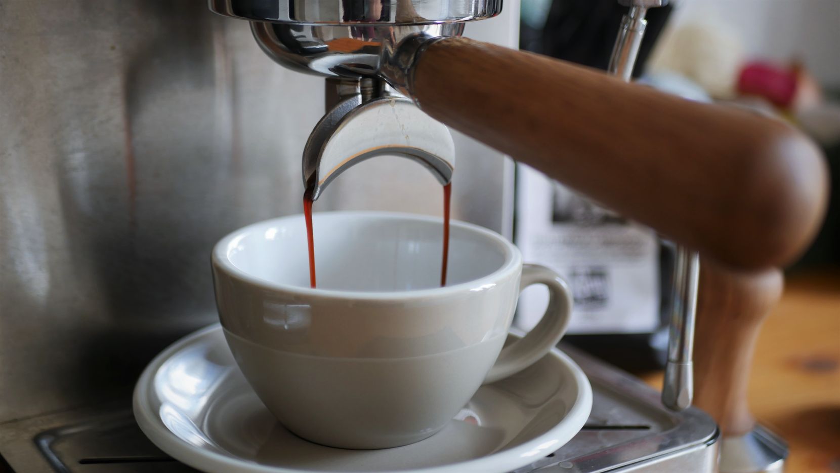 Man sieht eine halbautomatische Kaffeemaschine, aus der Espresso in eine graue Tasse fliesst.