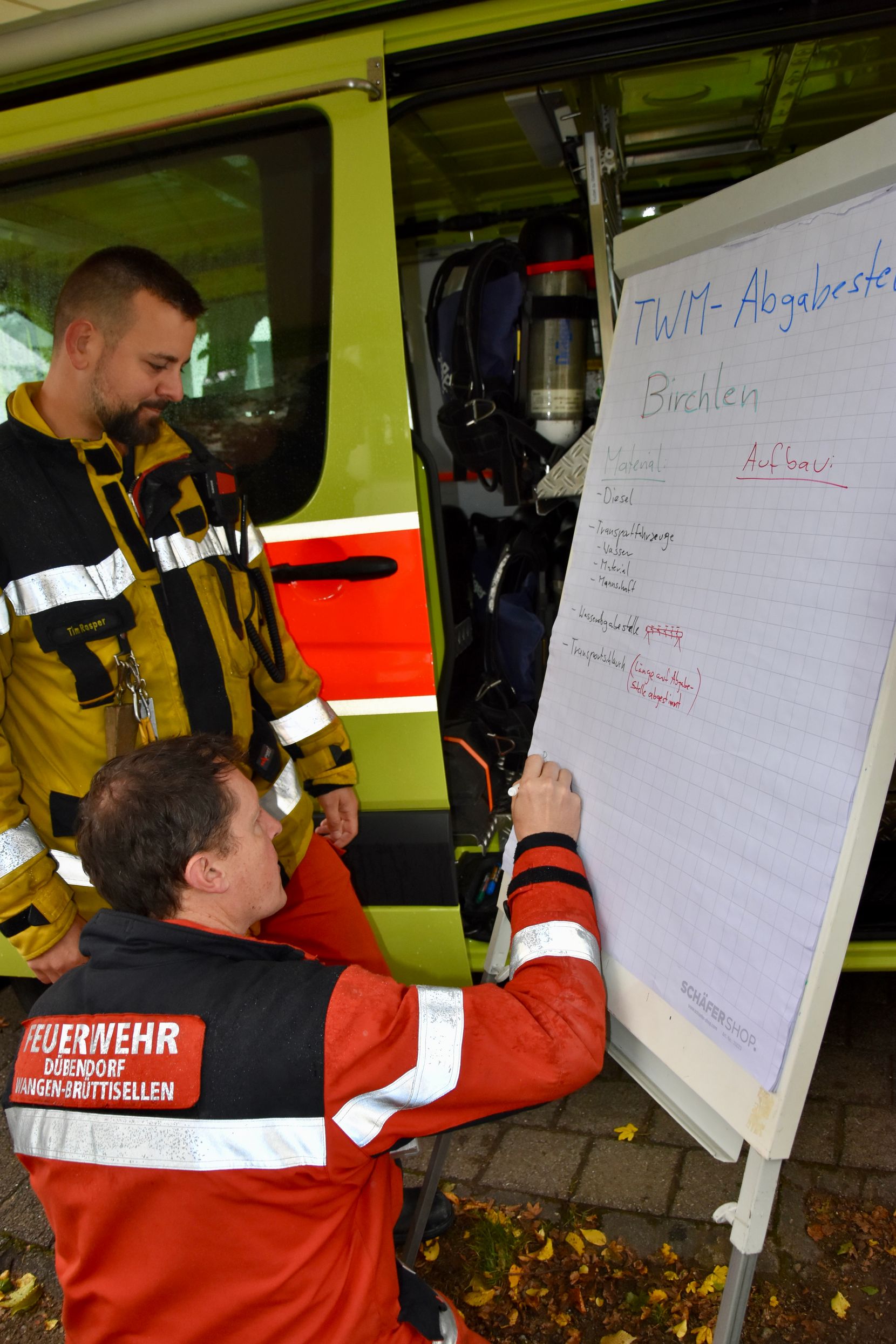 Ein Feuerwehrmann schreibt seine Erkenntnisse auf ein grosses Papier.