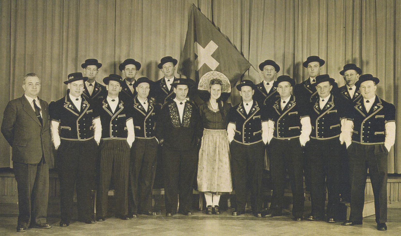 Eine Schwarzweiss-Aufnahme die die Gruppe Alpenrösli, bestehend aus 15 Männern und einer Frau, zeigt.