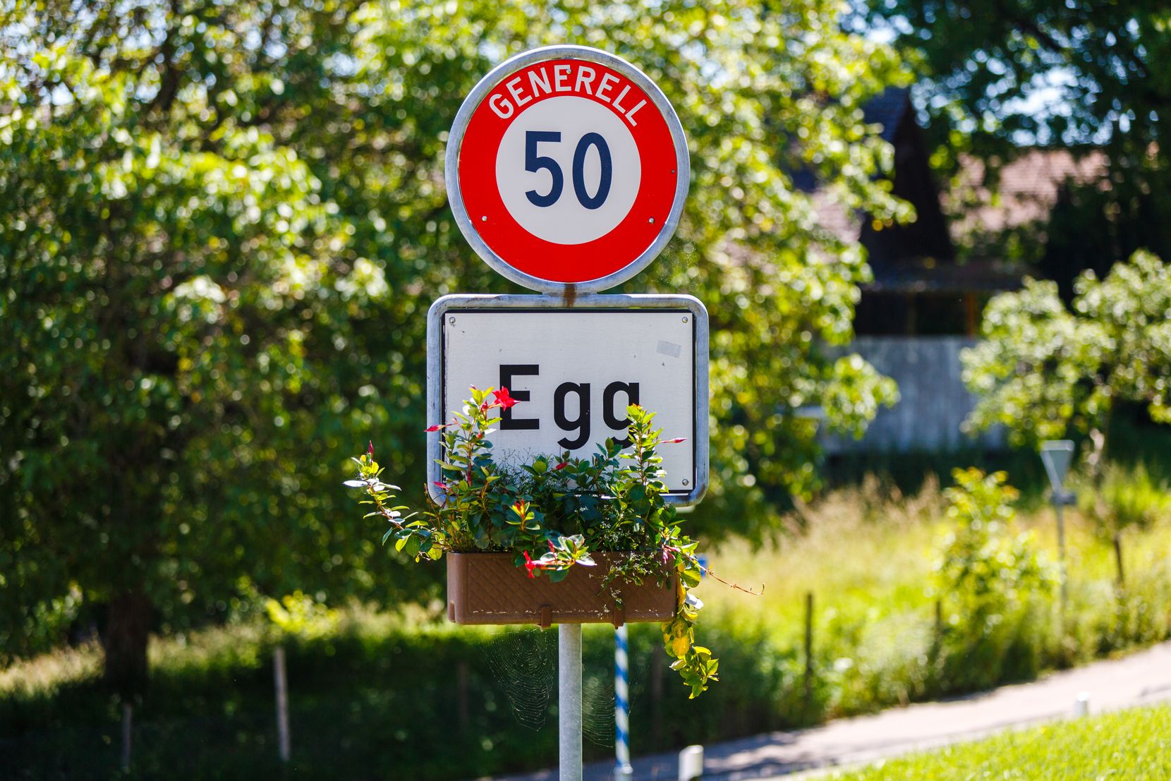 Ortschild der Gemeinde Egg mit Blumen.