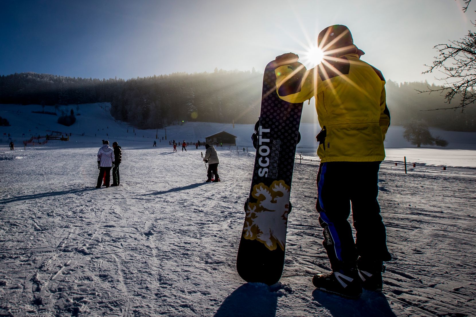 Ein Snowboarder mit Brett bei Sonnenuntergang.