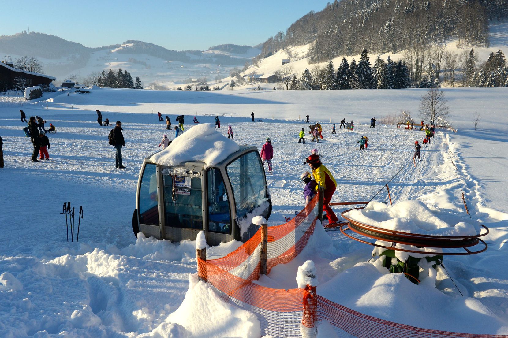 Viele Menschen betreiben Schneesport an einem Skilift im Sonnenschein.